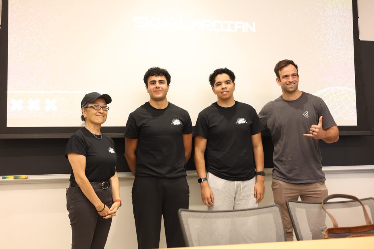 Alex and Nicolas with two others in front of a projector screen.